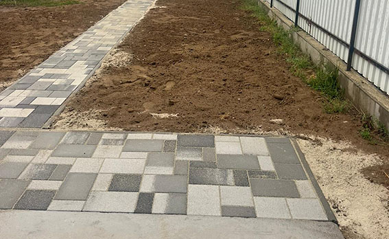 Acera doble de mosaico gris antracita junto a la valla